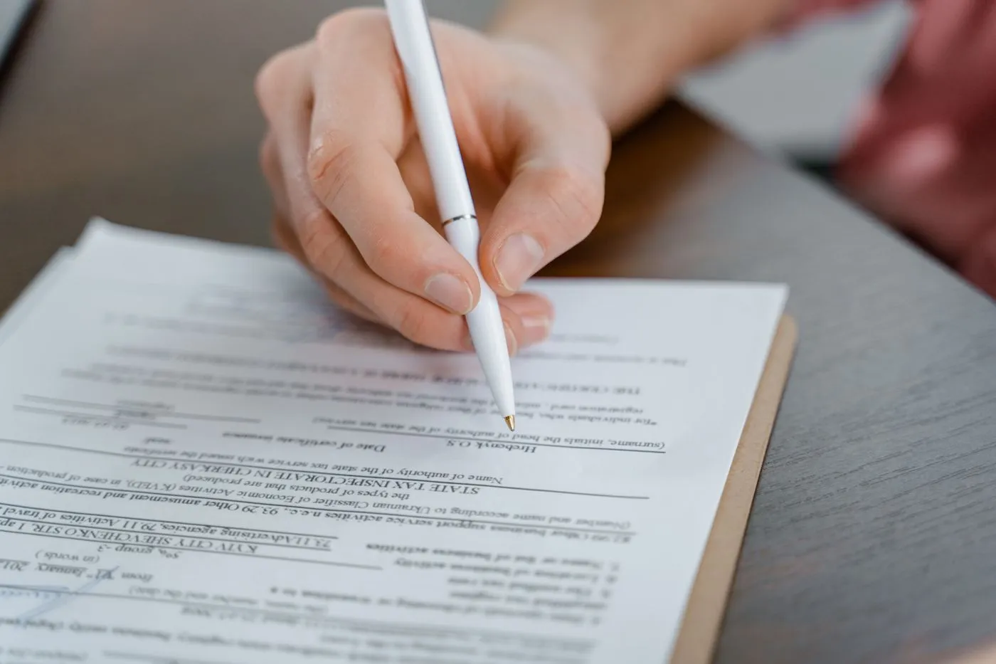 Hand unterschreibt ein Dokument mit einem Stift